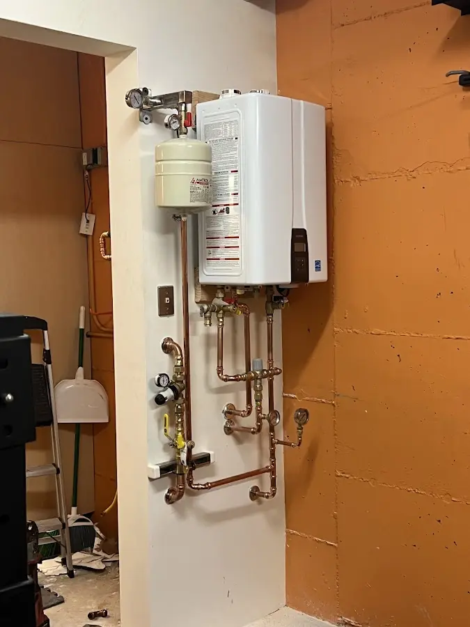 Plumbing technician inspecting water heater connections in Guilford
